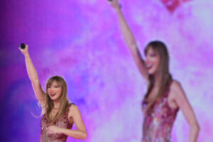 Taylor Swift sorri com um braço erguido enquanto o telão repete a imagem durante show em Buenos aires